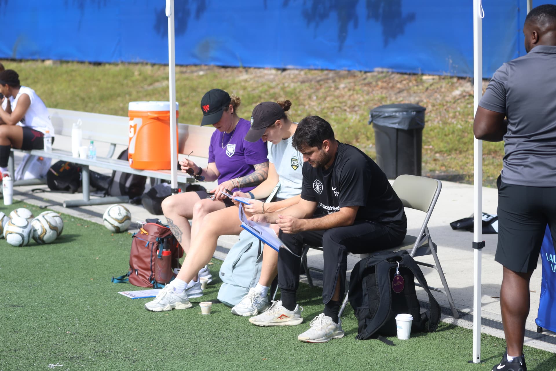 Scouts taking notes on the sideline at an OPSM event